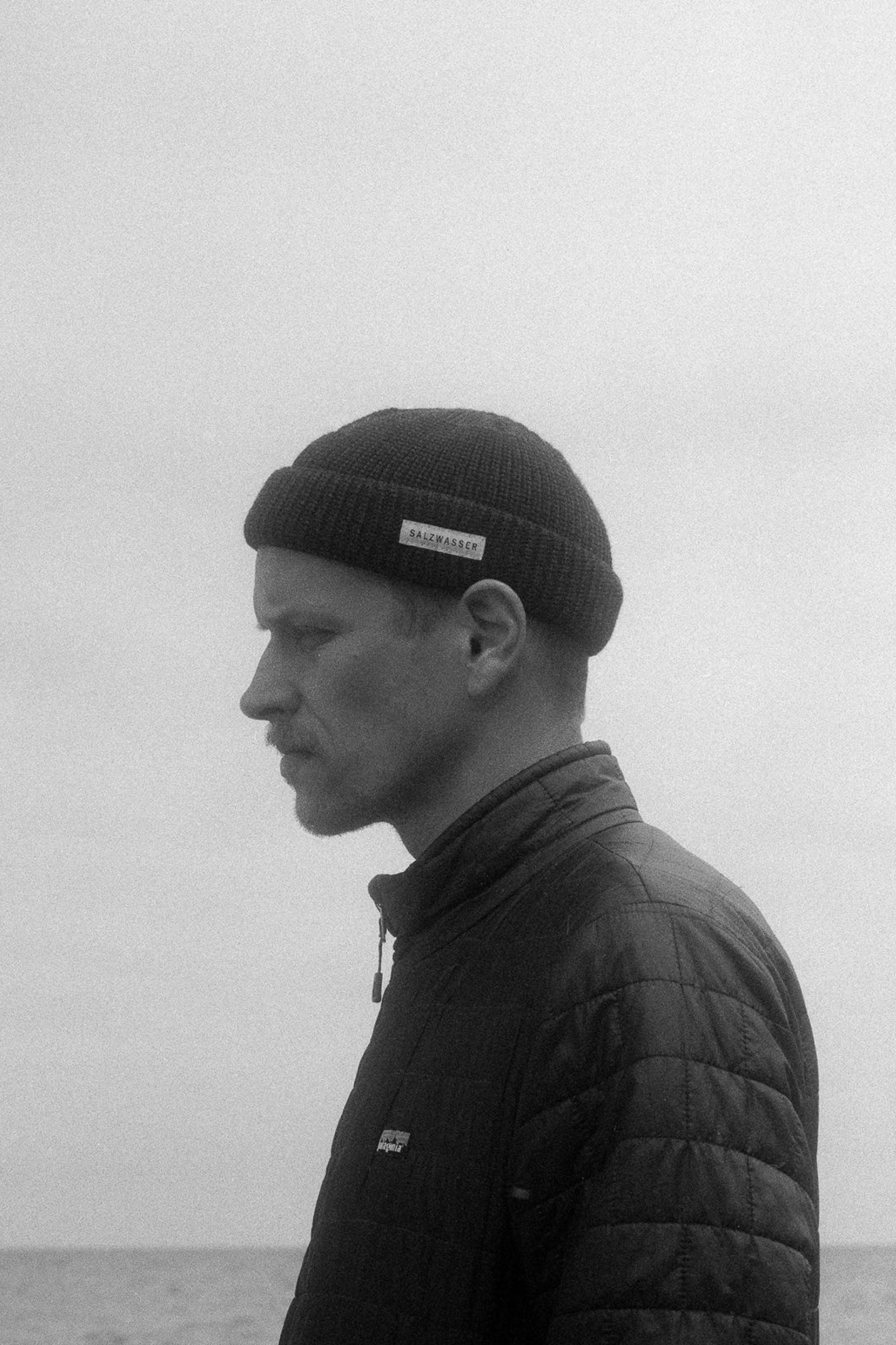 Mann trägt am Strand Fisherman Mütze von SALZWASSER aus Merinwolle