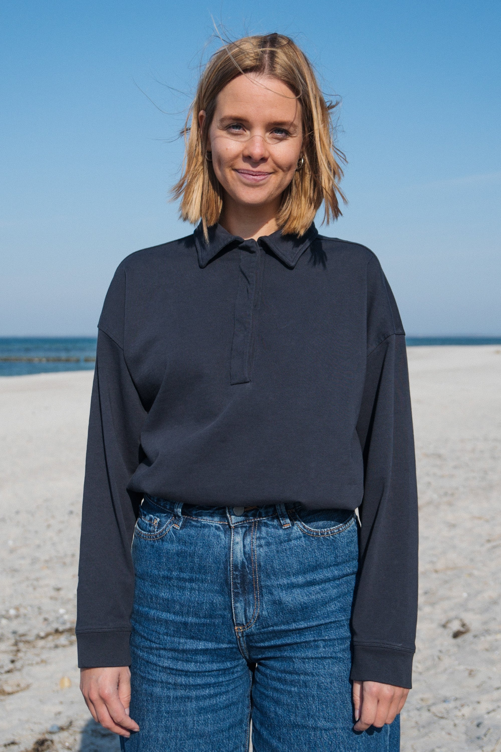 Frau trägt GOTS-zertifiziertes dunkelblaues Polo Longsleeve von SALZWASSER