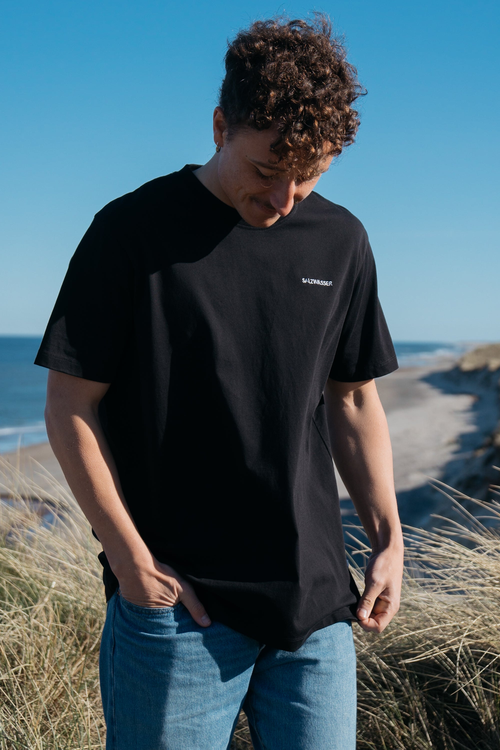 Mann trägt GOTS-zertifiziertes Schwarz-farbiges T-Shirt von SALZWASSER _men