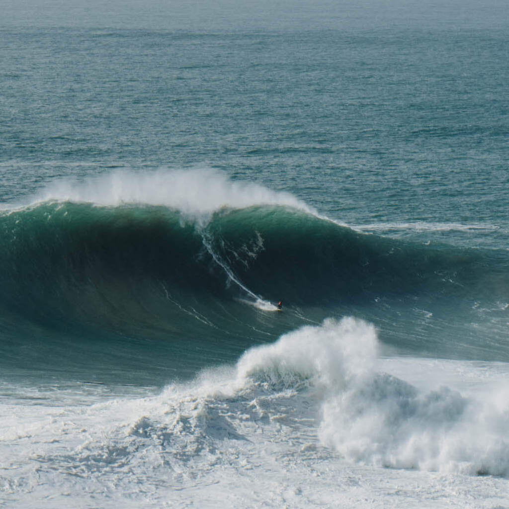 Surfer surft auf Riesenwelle in Nazare, Portugal