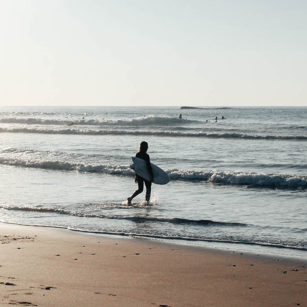 Laurenz Steierl läuft mit Surfbrett ins Wasser am Praia Amado