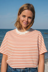 Frau trägt nachhaltiges Heavy T-Shirt von SALZWASSER in Orange-Naturweiß