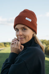 Frau trägt Strickmütze aus Norddeutschland: 100% weiche Merinowolle, zeitloses Design. Luxus für Haut und Umwelt. Handgefertigt, warm und leicht.