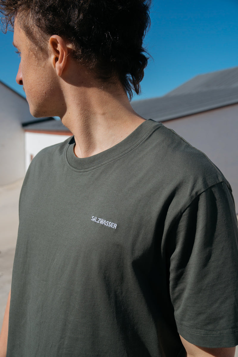 Mann trägt GOTS-zertifiziertes Oliv-farbiges T-Shirt von SALZWASSER