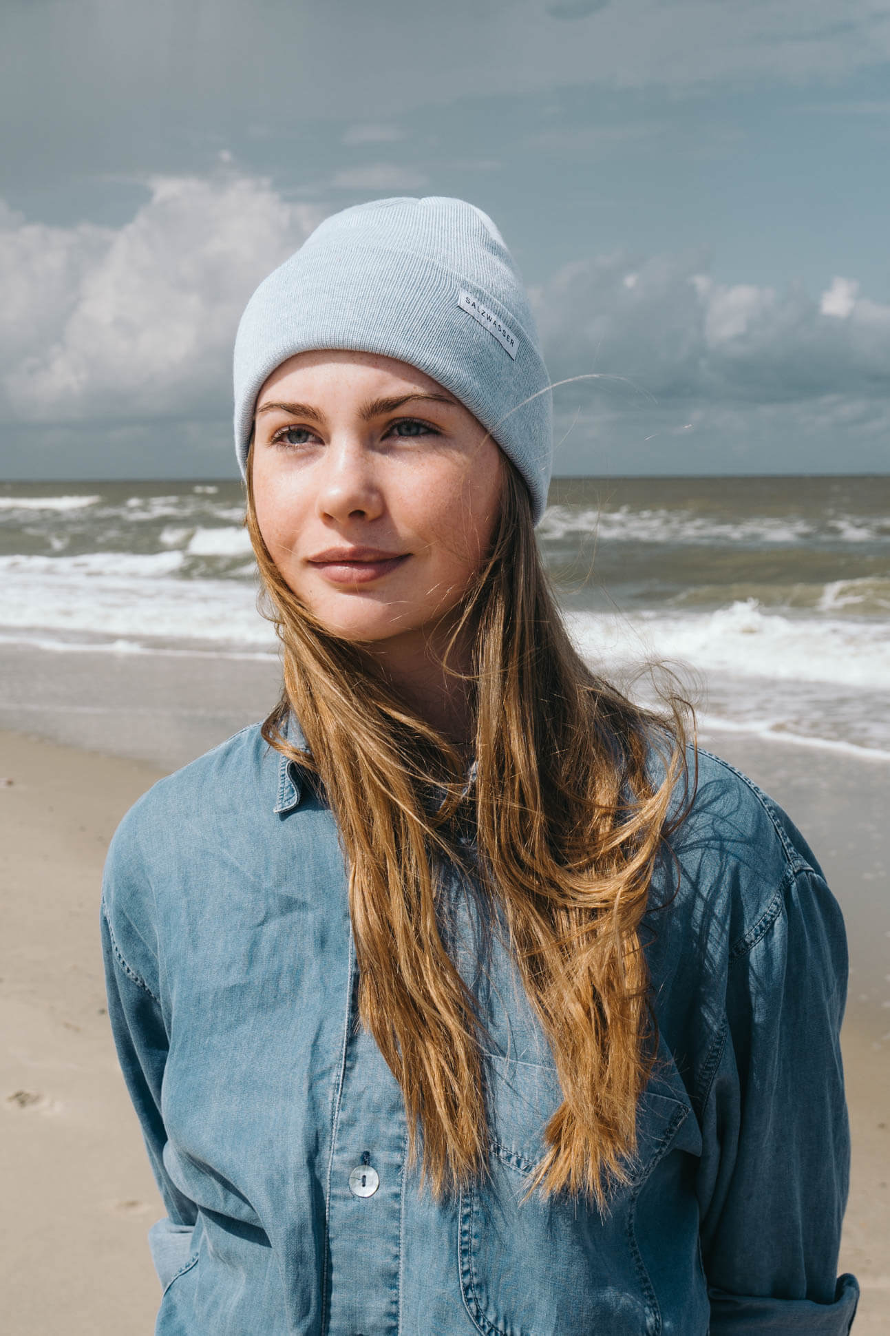 Frau trägt hellblaue SALZWASSER Mütze aus Merinowolle an der Nordseeküste
