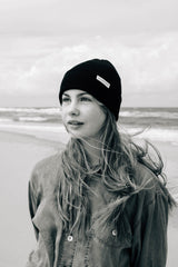 Frau trägt SALZWASSER Mütze mit plastikfreiem Label am Meer