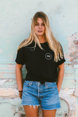 Frau trägt schwarzes SALZWASSER Shirt mit Wellenlogo _women